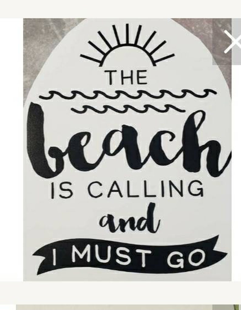 May include: White sign with black text that reads "THE BEACH IS CALLING and I MUST GO." The design includes a sun, waves, and a banner. The sign is a decorative item.