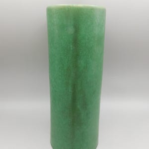 May include: A tall, cylindrical vase with a textured, mottled green surface. The vase has a simple, elegant design and a slightly flared top. The green color is consistent throughout the vase, creating a cohesive look. This decorative vase is suitable for home decor.