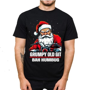 Può includere: Una maglietta nera con una grafica di un Babbo Natale scontroso che guida una moto. Il testo "GRUMPY OLD GIT BAH HUMBUG" è stampato sulla maglietta.
