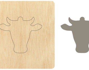 May include: A wooden cutout of a cow's head. The cutout is on a light brown wooden background. The cow's head is outlined in black.