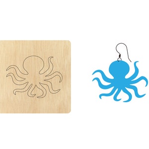 Puede incluir: Un recorte de madera de un pulpo con un pendiente de pulpo azul. El pendiente tiene un gancho negro.