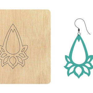 Puede incluir: Una plantilla de corte por láser para hacer pendientes. La plantilla está sobre una superficie de madera y muestra un pendiente en forma de lágrima con un diseño floral.