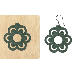 Puede incluir: Un par de pendientes de cuero verde oscuro con forma de flor con un centro recortado. Los pendientes se muestran sobre una superficie de madera.