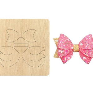 Puede incluir: Una plantilla de madera para hacer un lazo con un lazo de purpurina rosa y dorado en el fondo.