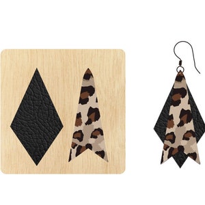 Puede incluir: Pendientes colgantes con forma de diamante de cuero negro superpuesto a un triángulo con estampado de leopardo. Los pendientes se muestran junto a una herramienta de corte de madera con las mismas formas. Los pendientes tienen un gancho para la oreja negro.