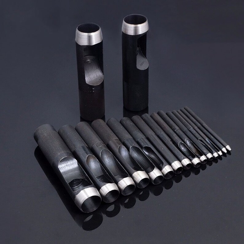 May include: A set of 17 black metal hole punch tools with silver edges. The tools are arranged in size order, with the largest tool at the top and the smallest tool at the bottom. The tools are used for punching holes in leather, fabric, and other materials.