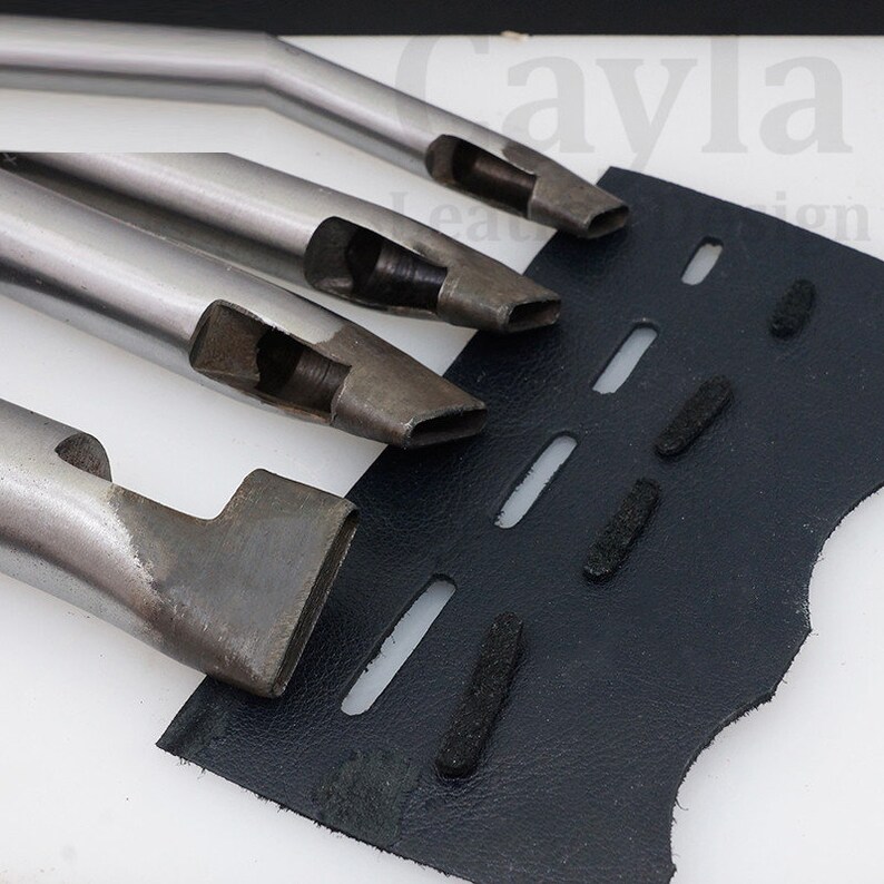 May include: Four metal leather hole punches of different sizes. The punches are arranged in order of size, with the largest punch at the top and the smallest punch at the bottom. The punches are on a blue leather surface with holes punched in it.