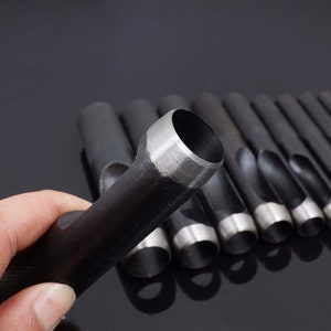 May include: A set of 10 round hole punches, made of metal, with different sizes. The punches are black with a silver edge. The punches are used for leather crafting.