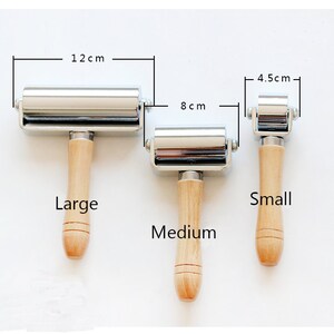 May include: Three metal and wood craft rollers in varying sizes. The largest roller is 12 cm wide, the medium roller is 8 cm wide, and the smallest roller is 4.5 cm wide. Each roller has a wooden handle.