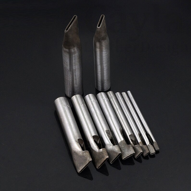 May include: A set of 11 leather hole punches, including two long punches with pointed tips and nine shorter punches with various shaped openings. The punches are made of metal and have a silver finish.