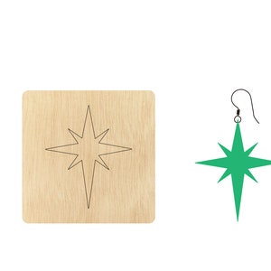 Puede incluir: Un recorte de madera de una estrella con un pendiente de estrella verde. El pendiente cuelga de un gancho plateado.