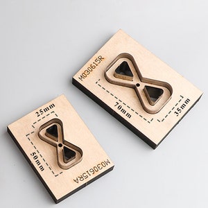 Pu&ograve; includere: Due matrici di taglio in legno a forma di clessidra con un triangolo all'interno. La matrice pi&ugrave; grande misura 70 mm per 35 mm ed &egrave; etichettata M030615R. La matrice pi&ugrave; piccola misura 50 mm per 25 mm ed &egrave; etichettata M030615RA.