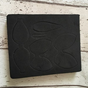 Puede incluir: Hoja de espuma negra con m&uacute;ltiples formas recortadas de hojas y p&eacute;talos. Esta es una plantilla de troquelado para manualidades.