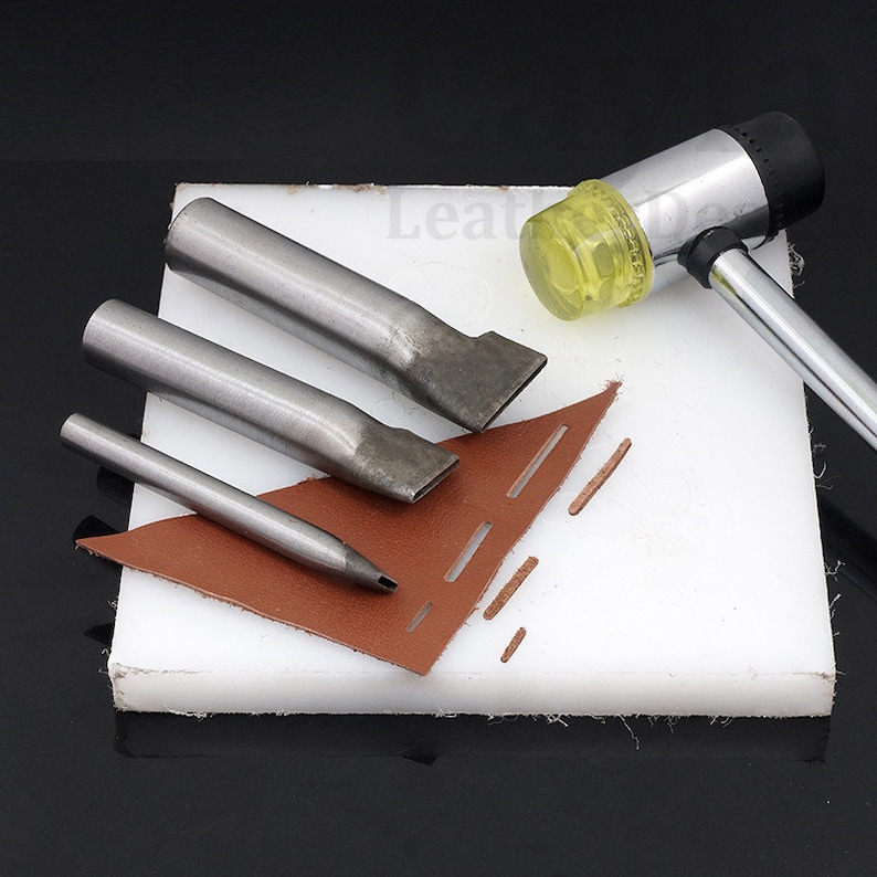 May include: A set of four leather crafting tools, including three different sized punches and a mallet with a yellow rubber head. The tools are on a white cutting mat with a piece of brown leather.
