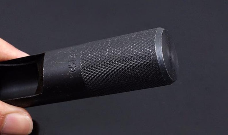 May include: A black metal punch tool with a textured handle and a 25mm hole. The tool is designed for punching holes in metal.