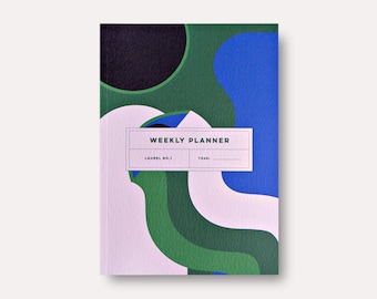 May include: A weekly planner with a colorful abstract design featuring shades of green, blue, black, and pink. The cover has the text "WEEKLY PLANNER" and "LAUREL NO. 1" in a white rectangle.