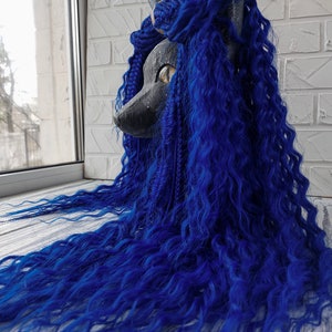 May include: A black and grey animal mask with blue curly hair. The mask has a long snout and large, golden eyes.