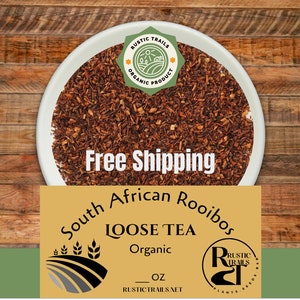 May include: A close-up of a bowl of loose leaf South African Rooibos tea. The tea is brown and has a slightly reddish hue. The tea is labeled as organic and is available in a 1 oz size. The text "Free Shipping" is visible in the image.