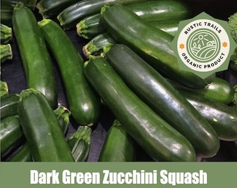 May include: A pile of dark green zucchini squash. The vegetables are long and cylindrical, with a smooth, glossy skin. The image includes a green banner with the text "Dark Green Zucchini Squash" and a "Rustic Trails Organic Product" logo.