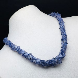 Op de afbeelding: Een ketting gemaakt van kleine, onregelmatige, lichtblauwe edelsteenchips. De ketting wordt getoond op een witte mannequinbuste.