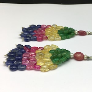 May include: A pair of earrings featuring a multi-coloured gemstone design. The earrings have a teardrop-shaped cluster of blue, pink, yellow and green gemstones. Each earring is topped with a white pearl and a silver post.