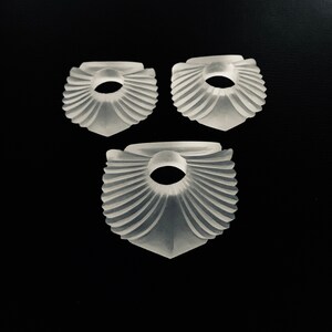 Puede incluir: Tres piezas blancas decorativas en forma de abanico con un agujero en el centro. Las piezas est&aacute;n hechas de un material transl&uacute;cido y tienen un dise&ntilde;o delicado e intrincado.