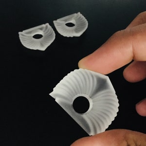 Puede incluir: Tres engranajes de pl&aacute;stico blanco con un dise&ntilde;o radial decorativo. Los engranajes tienen un agujero central y son transl&uacute;cidos.