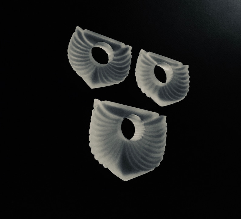 Puede incluir: Tres anillos de pl&aacute;stico blanco decorativos con un dise&ntilde;o texturizado en forma de abanico. Los anillos tienen un agujero en el centro.