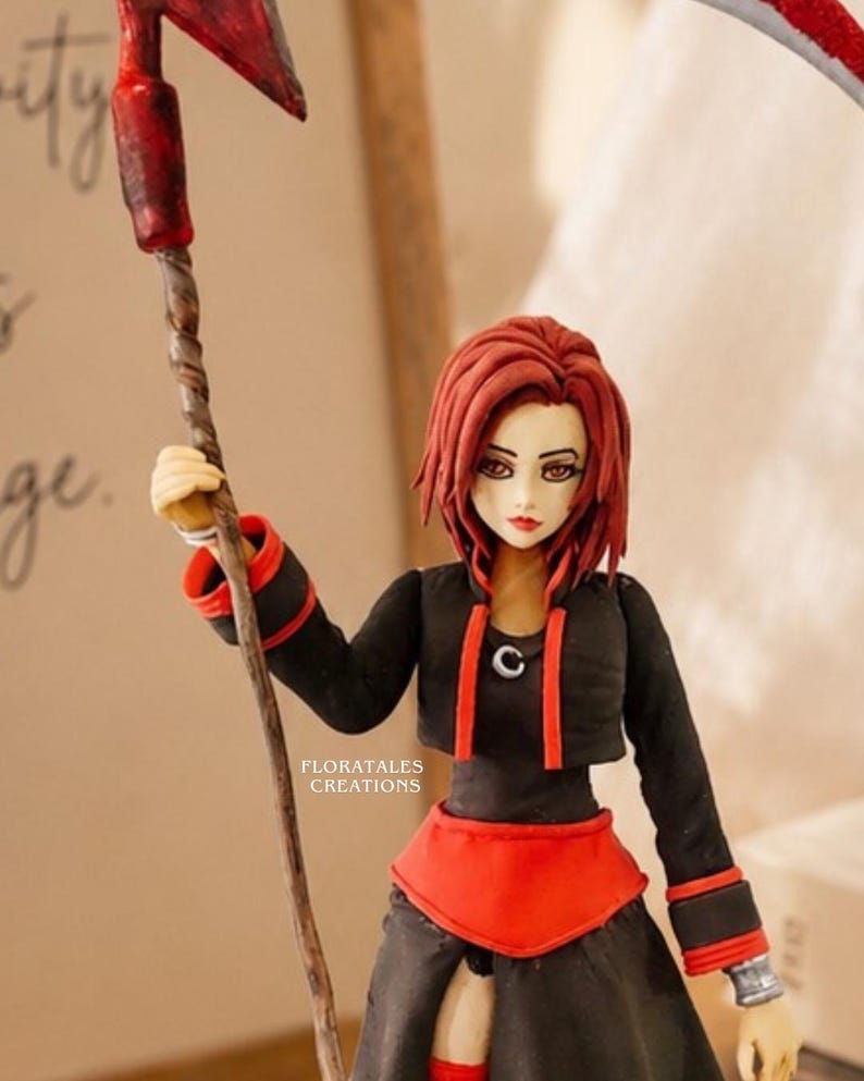 May include: A handcrafted figurine of a female anime character with red hair, wearing a black outfit with red accents. She holds a scythe with a red blade. The figurine is detailed with a stylized design. The text "FLORATALES CREATIONS" is visible.