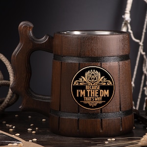 May include: A dark brown wooden beer mug with a large handle. The mug has a metal interior and a black and gold emblem that reads "BECAUSE I'M THE DM THAT'S WHY". The mug is designed to look like a barrel.