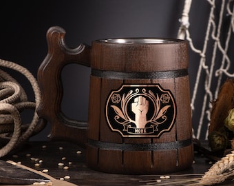 May include: A dark brown wooden beer mug with a decorative handle. The mug features a black and copper emblem with a fist and the word "MONK". The mug has a stainless steel interior and is banded with black trim.