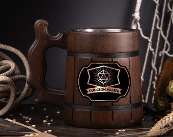 May include: A wooden beer mug with a dark brown finish, featuring a decorative handle and a metal interior. The mug has a black label with the words "DUNGEON MASTER" and a D20 die symbol.