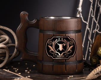 May include: A dark brown wooden beer mug with a decorative handle and a metal interior. The mug features a black and copper emblem with a sword, axe, and the word "FIGHTER".