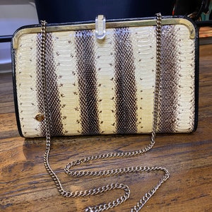May include: A white and brown striped snakeskin clutch bag with a gold chain strap.
