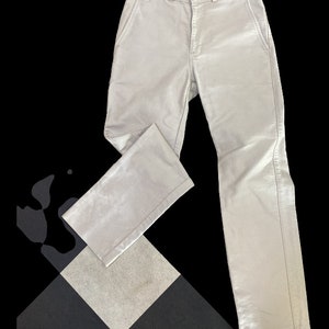 Può includere: Un paio di pantaloni grigi chiari a gamba dritta e con chiusura a bottone.