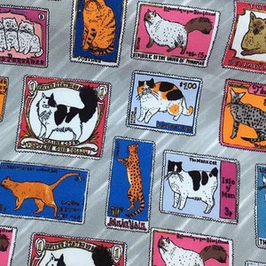 May include: A gray fabric with a repeating pattern of colorful postage stamps featuring different breeds of cats. Each stamp has a different country of origin and a price in a foreign currency. The stamps are surrounded by a gray background with a diagonal stripe pattern.