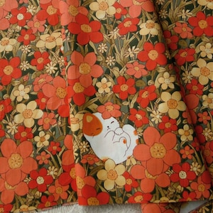 May include: A fabric with a repeating pattern of white cats sleeping in a field of orange and yellow flowers on a dark green background.