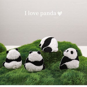 Puede incluir: Cuatro parches de peluche de panda blanco y negro sobre un fondo de musgo verde. Los parches están bordados y tienen una textura peluda. El texto "I love panda" está escrito sobre los parches.