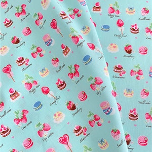 May include: A light blue fabric with a repeating pattern of strawberries, macarons, cakes, and candy. The pattern also includes the words "Happy time", "Love sweets", "Very cotton", "Candy fruit", "Small cake", "Macaroons", and "Strawberry".