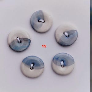 Könnte beinhalten: Fünf Keramikknöpfe mit weißem und blauem Aquarelldesign. Jeder Knopf hat ein Loch zum Nähen. Die Zahl "15" ist rot gedruckt.