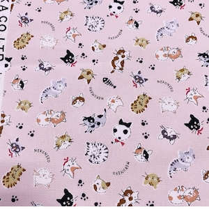 May include: Pink fabric with a repeating pattern of cats in various poses. The cats are drawn in a cartoon style and are in different colors, including black, white, brown, and gray. The fabric also has a repeating pattern of paw prints and the word "NEKONECO" in black.