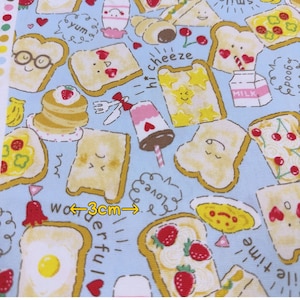 May include: Light blue fabric with a repeating pattern of cartoon toast, pancakes, and milkshakes. The design includes text bubbles with words like "yum" and "love". The fabric is approximately 3cm wide.