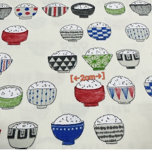 May include: White fabric with a repeating pattern of bowls filled with rice. The bowls are decorated with various geometric patterns in black, white, red, blue, and green. The text "[<--2cm-->]" is printed on the fabric.