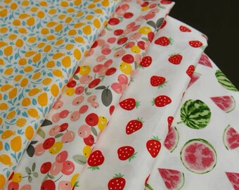 Könnte beinhalten: Gefaltete Stoffmuster mit Fruchtmustern. Die Designs umfassen Zitronen, Kirschen, Erdbeeren und Wassermelonenstücke auf weißem Hintergrund. Die Farben sind Gelb, Rot, Rosa und Grün.
