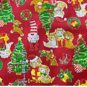 May include: Red fabric with a repeating pattern of Christmas trees, kittens, presents, and candy canes. The fabric is 6 inches tall and 5 inches wide.