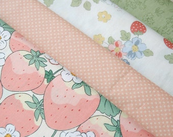 May include: Four different fabric swatches with various patterns. The top swatch is green with a white floral pattern. The second swatch is white with a pink polka dot pattern. The third swatch is white with a pink strawberry and white flower pattern. The bottom swatch is white with a pink strawberry and green leaf pattern.