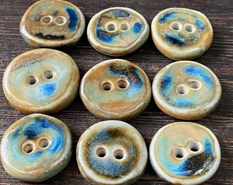 May include: Ten ceramic buttons with a blue and brown glaze. The buttons have two holes each.