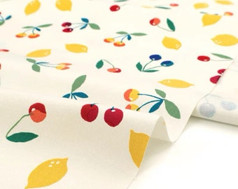 May include: White fabric with a repeating pattern of yellow lemons and red, orange, and blue cherries. The fabric is folded over on itself, showing the pattern on both sides.