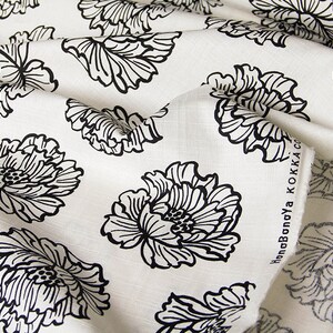 May include: White fabric with a black floral pattern. The fabric has a linen texture and the flowers are stylized and detailed. The text "HonobonoYa KOKKA CO." is visible on the edge of the fabric.