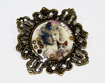 Old style brooch with an image of little girl holding her cat